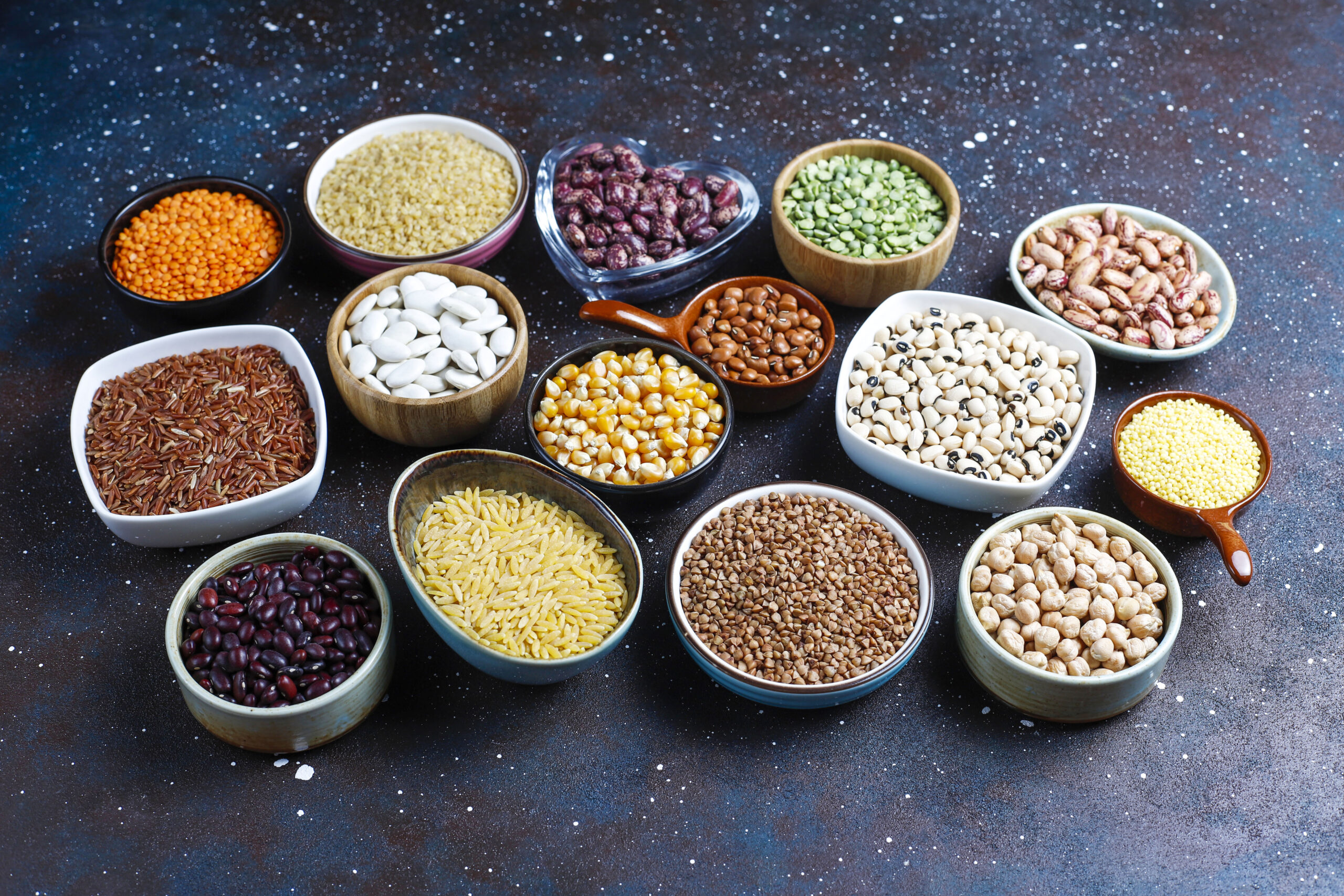legumes and beans assortment in different bowls on light stone b